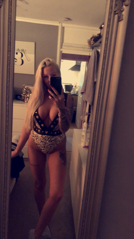 Angela Marie In black lingerie standing in front of a mirror taking a selfie