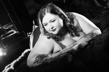 Monochrome image of a photo shoot with UK cam girl Athena Witch laying on her front and looking off frame