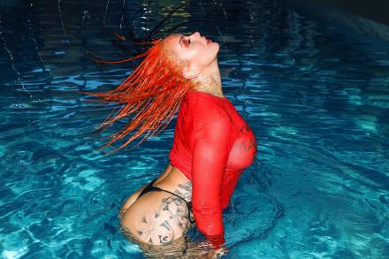 Brooksie Brooks throws her red hair back as she raises from a swimming pool at night